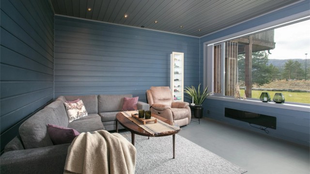 Stuen har god plass til stor sofagruppe og store vindusflater mot naturen utenfor.