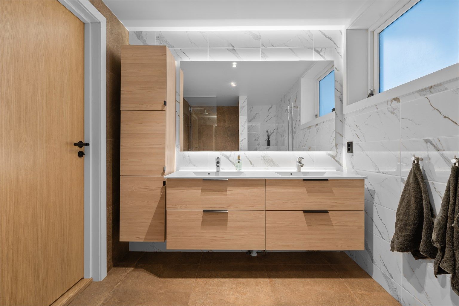 Badet har dobbel vask og rikelig med lagringsplass i skuffer og høyskap.