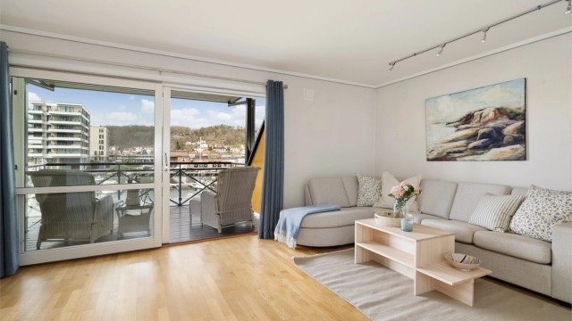 Store skyvedører i glass åpner opp mot balkongen og trekker utsikten og lyset inn i stuen.