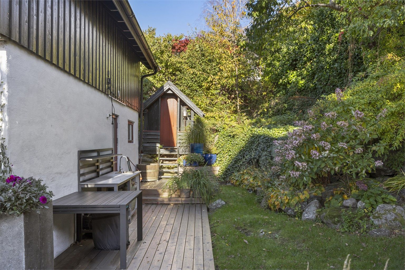 Mot nord er det en markterrasse på ca. 33 m² med utekjøkken og et praktisk vedskjul.