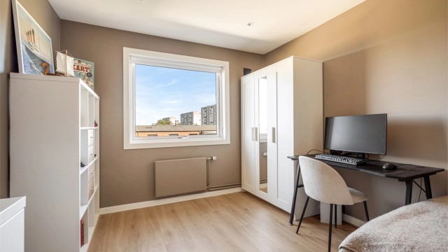 Leilighetens andre soverom har plass til seng, skrivebord og garderobeskap.