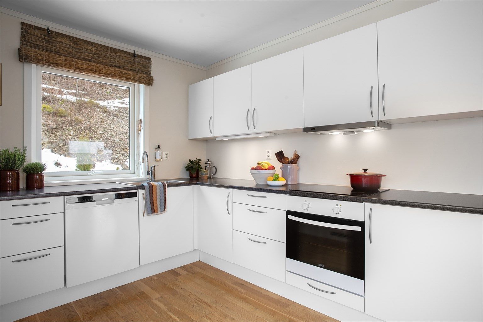 Kjøkken med innredning med slette fronter. Benkeplate med laminert flate og nedfelt oppvaskkum.