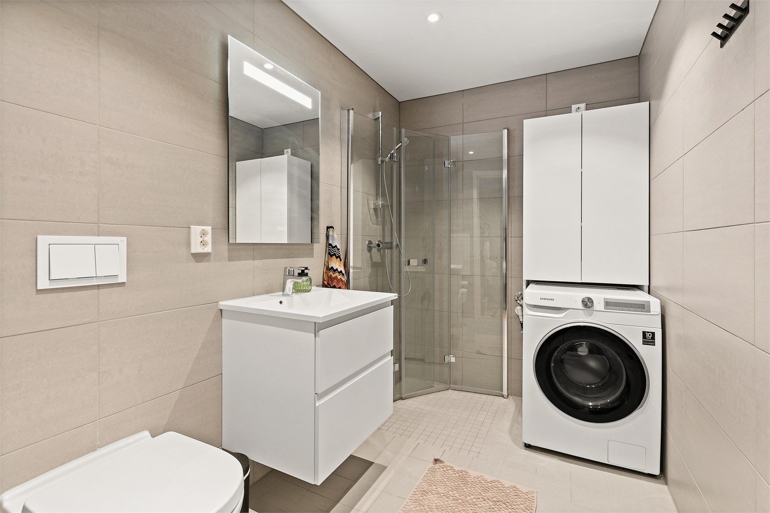 Stilrent baderom med flislagt gulv med gulvvarme og flislagte vegger.