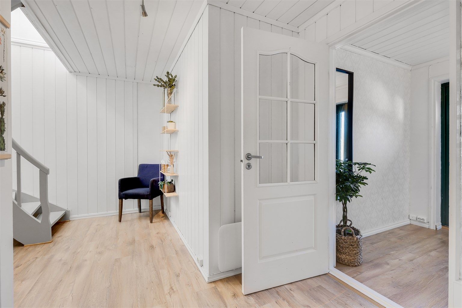 Gangen fører rett inn i hallen med svingtrapp opp til stua og hovedetasjen.