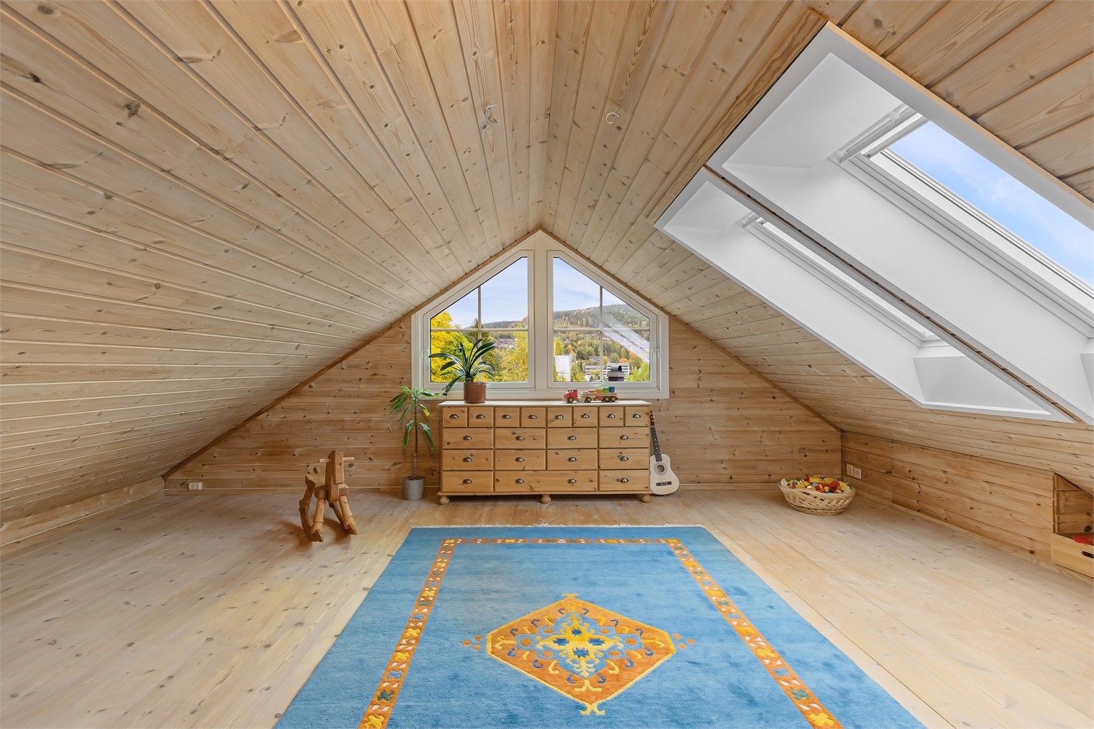 Innredet loftstue med heltre furugulv, takvinduer og gavlvindu som slipper inn rikelig med lys.