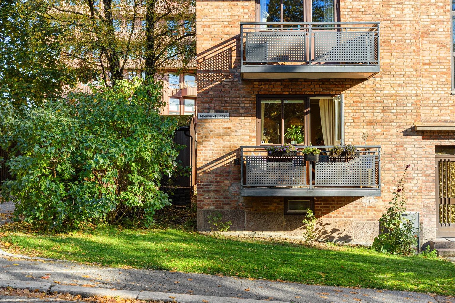 Den klassiske teglsteinsfasaden fra 1934 vitner om solid byggekunst og tidløs arkitektur. Leilighetens balkong ligger over en skjermet gressplen, omgitt av frodig grønt, med følelsen av å bo i en rolig oase midt i byen.