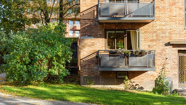 Den klassiske teglsteinsfasaden fra 1934 vitner om solid byggekunst og tidløs arkitektur. Leilighetens balkong ligger over en skjermet gressplen, omgitt av frodig grønt, med følelsen av å bo i en rolig oase midt i byen.