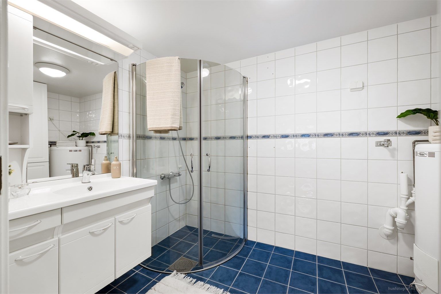 Badet har dusjhjørne med innfellbare dusjdører av glass.