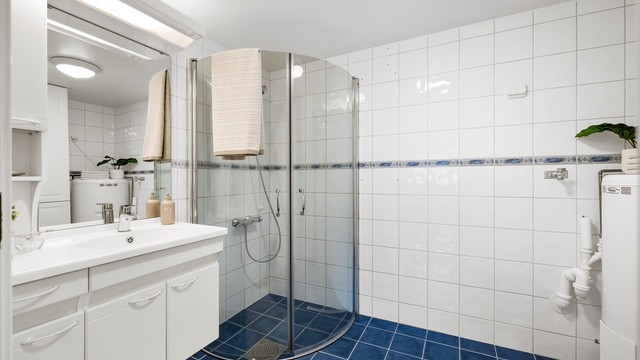 Badet har dusjhjørne med innfellbare dusjdører av glass.