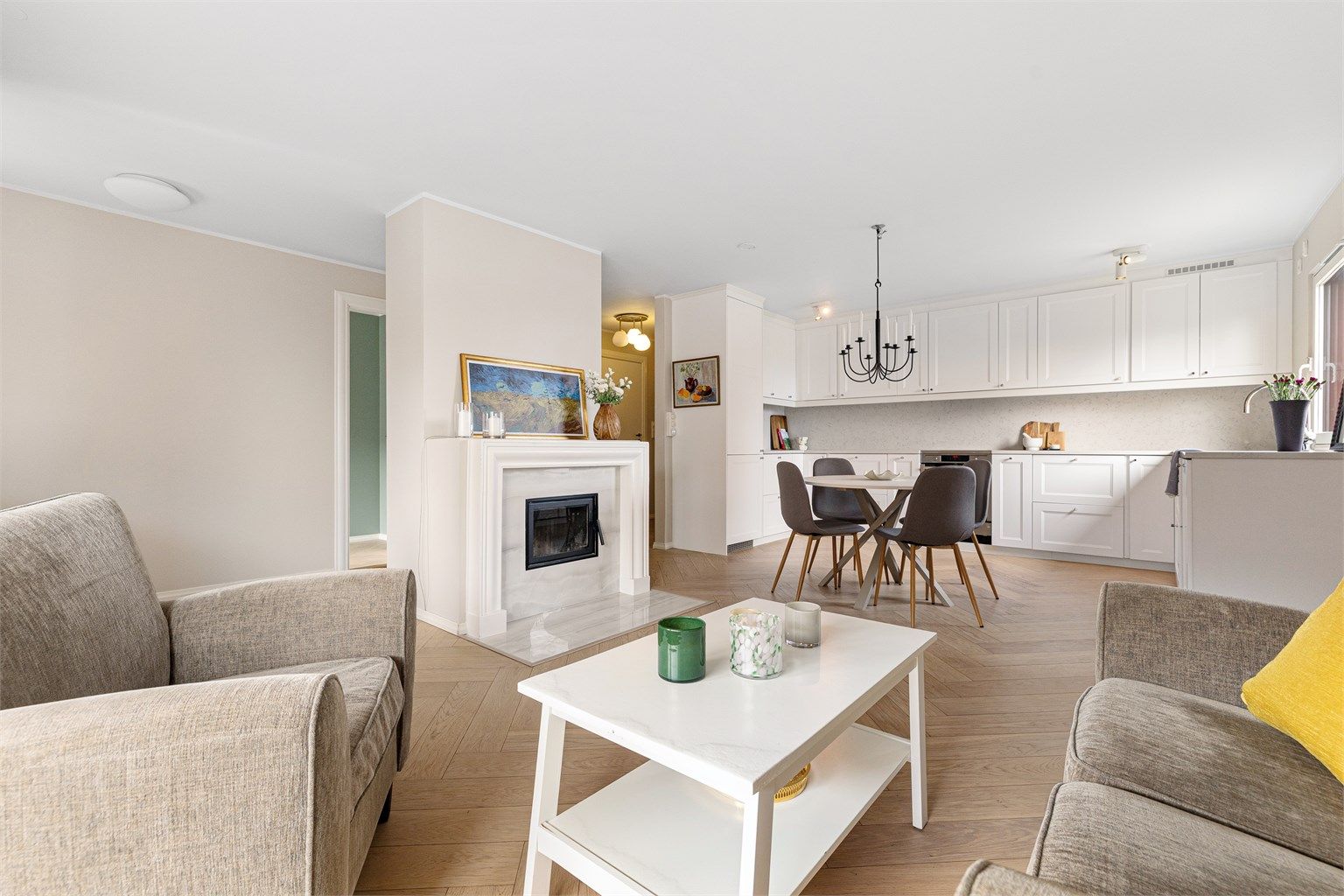 Den åpne løsningen mellom stue og kjøkken skaper en lys og sosial sone, med god plass til både sofagruppe og spisebord.