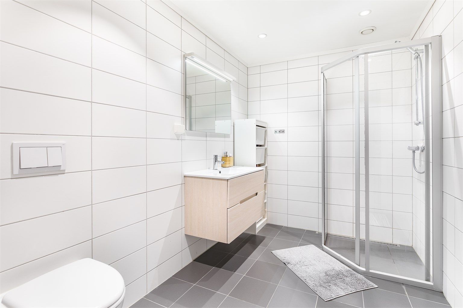 På badet er gulvet og veggene utført med fliser, himlingen med innfelte LED-spotter som kan dimmes.
