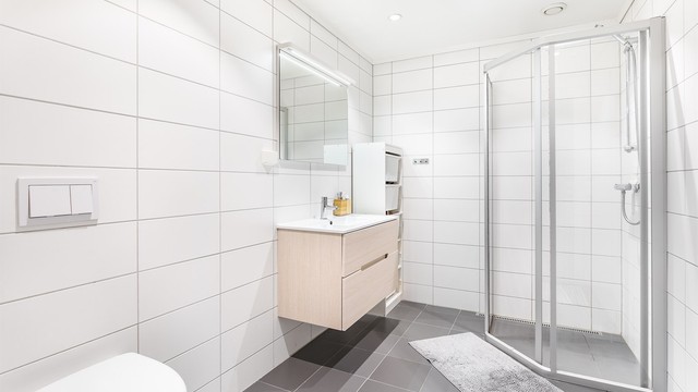 På badet er gulvet og veggene utført med fliser, himlingen med innfelte LED-spotter som kan dimmes.