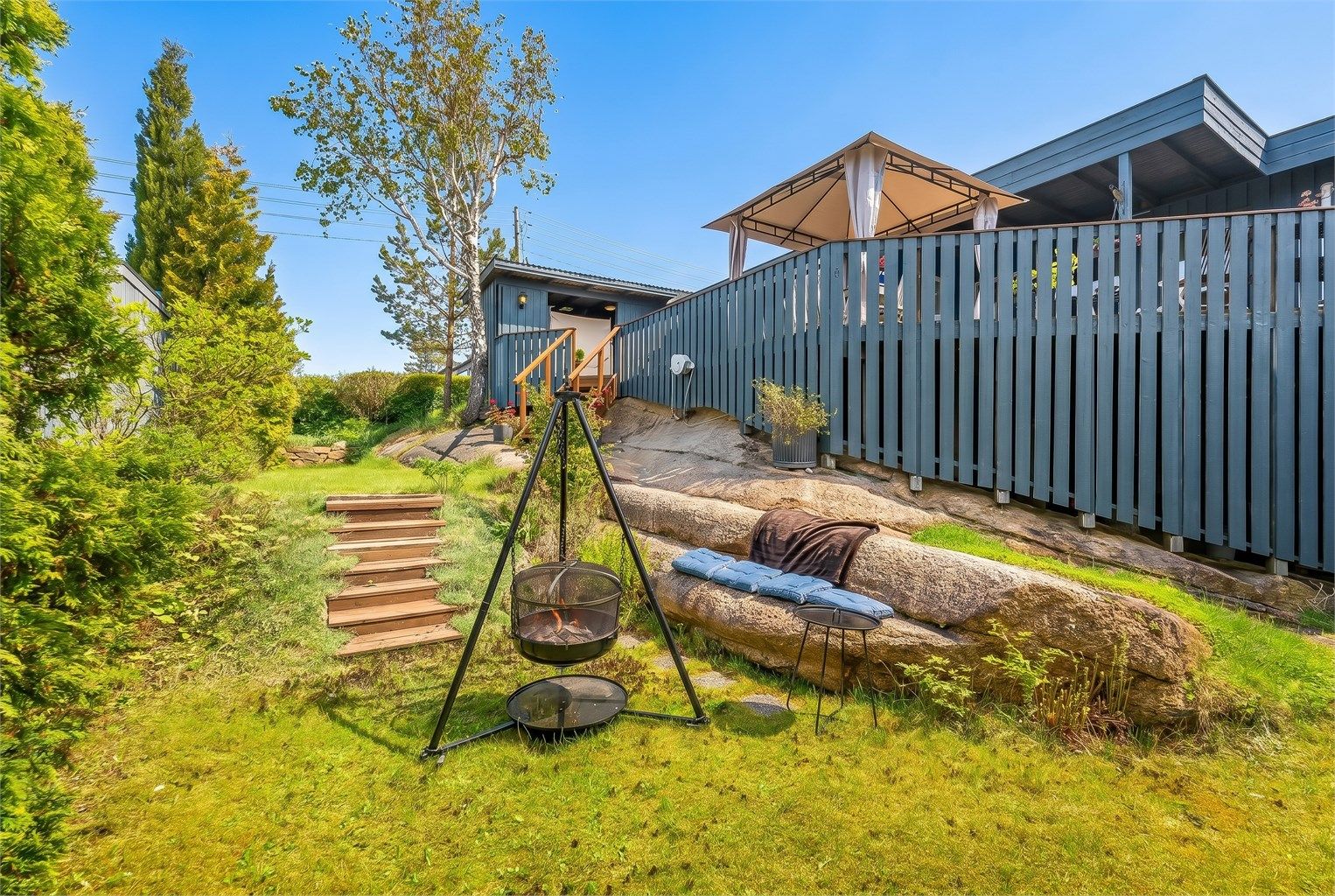 Den usjenerte hagen har en fin kombinasjon av plen og synlig fjell, som gir en sjarmerende ramme rundt uteplassen.
