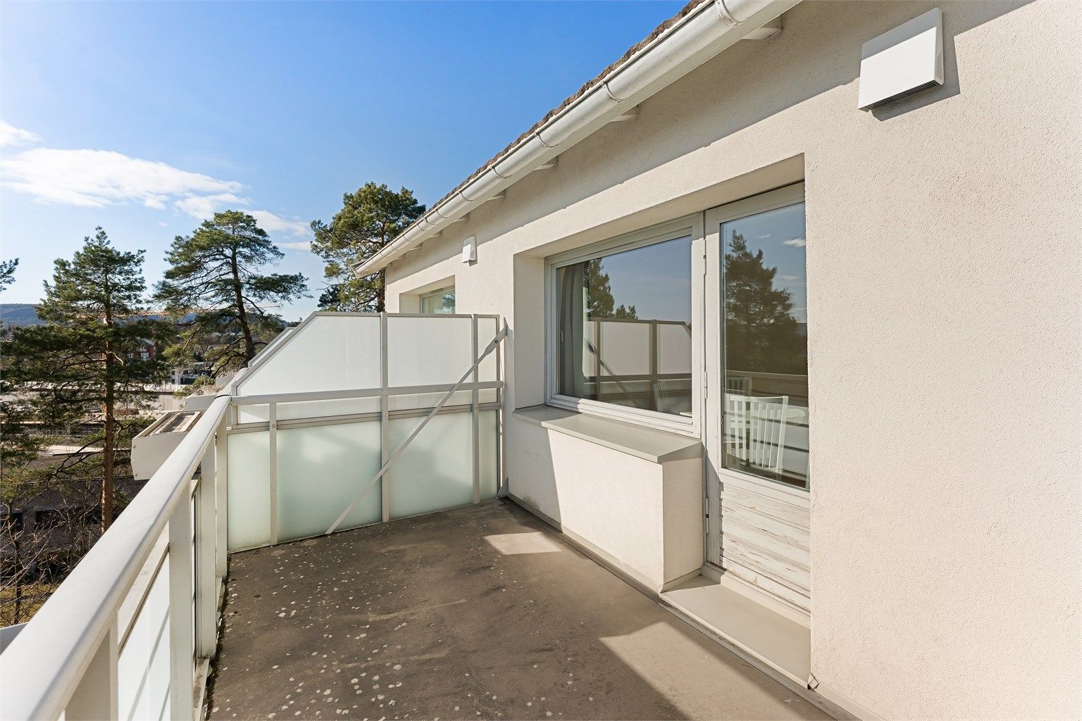 Balkongen har betongdekke og rekkverk av metall og glass.