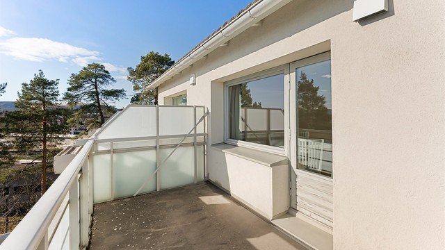 Balkongen har betongdekke og rekkverk av metall og glass.