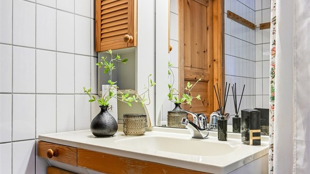 Badet er innredet med badekar, innredning med nedfelt servant og speilskap over servanten.