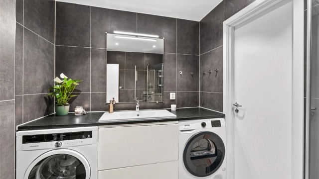 Badet har en praktisk benkeløsning med opplegg for vaskemaskin og tørketrommel.