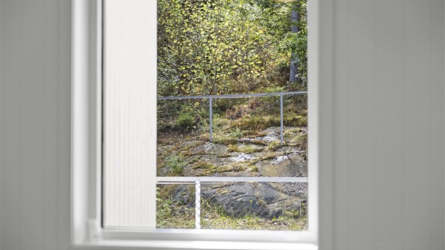 Utsikt fra soveromsvinduet mot grøntområde.