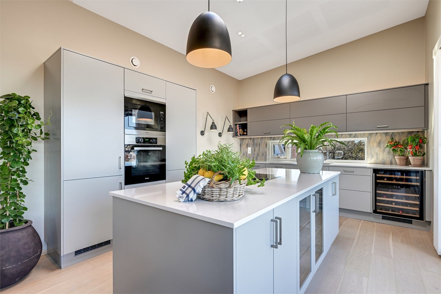 En stor kjøkkenøy med benkeplate i stein fungerer som et sosialt midtpunkt og en praktisk arbeidsflate.