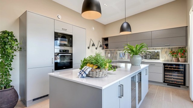 En stor kjøkkenøy med benkeplate i stein fungerer som et sosialt midtpunkt og en praktisk arbeidsflate.