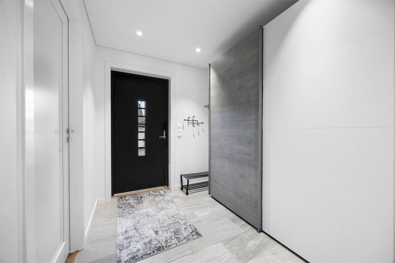 Entré med flislagt gulv, gulvvarme og skyvedørsgarderobe.