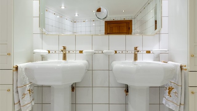 Doble søyleservanter med armaturer i messingutførelse og stort speil.