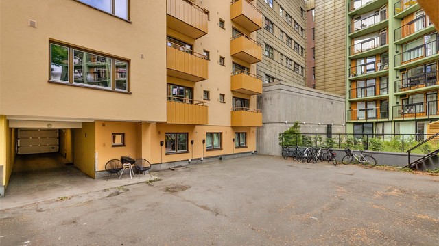 Felles tomt er opparbeidet med asfalterte fellesarealer, sykkelparkering og en bakgård med søppelkasser.