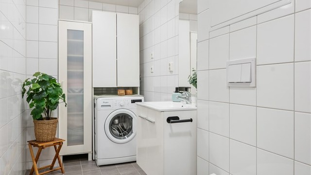 Praktisk innredet bad med vegghengt toalett og opplegg for vaskemaskin.