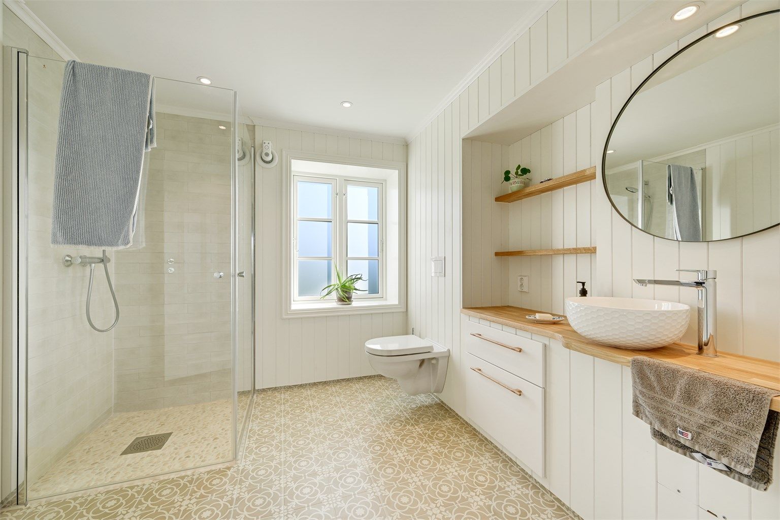 Badet i første etasje er plassbygget og smakfullt utformet, med fliser på gulv og i dusjsonen, øvrige vegger med panel og behagelige varmekabler i gulvet. 