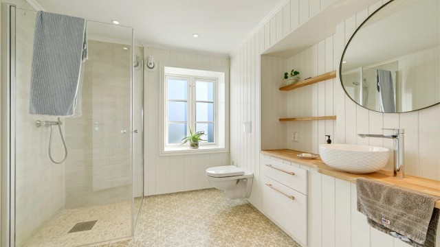 Badet i første etasje er plassbygget og smakfullt utformet, med fliser på gulv og i dusjsonen, øvrige vegger med panel og behagelige varmekabler i gulvet.