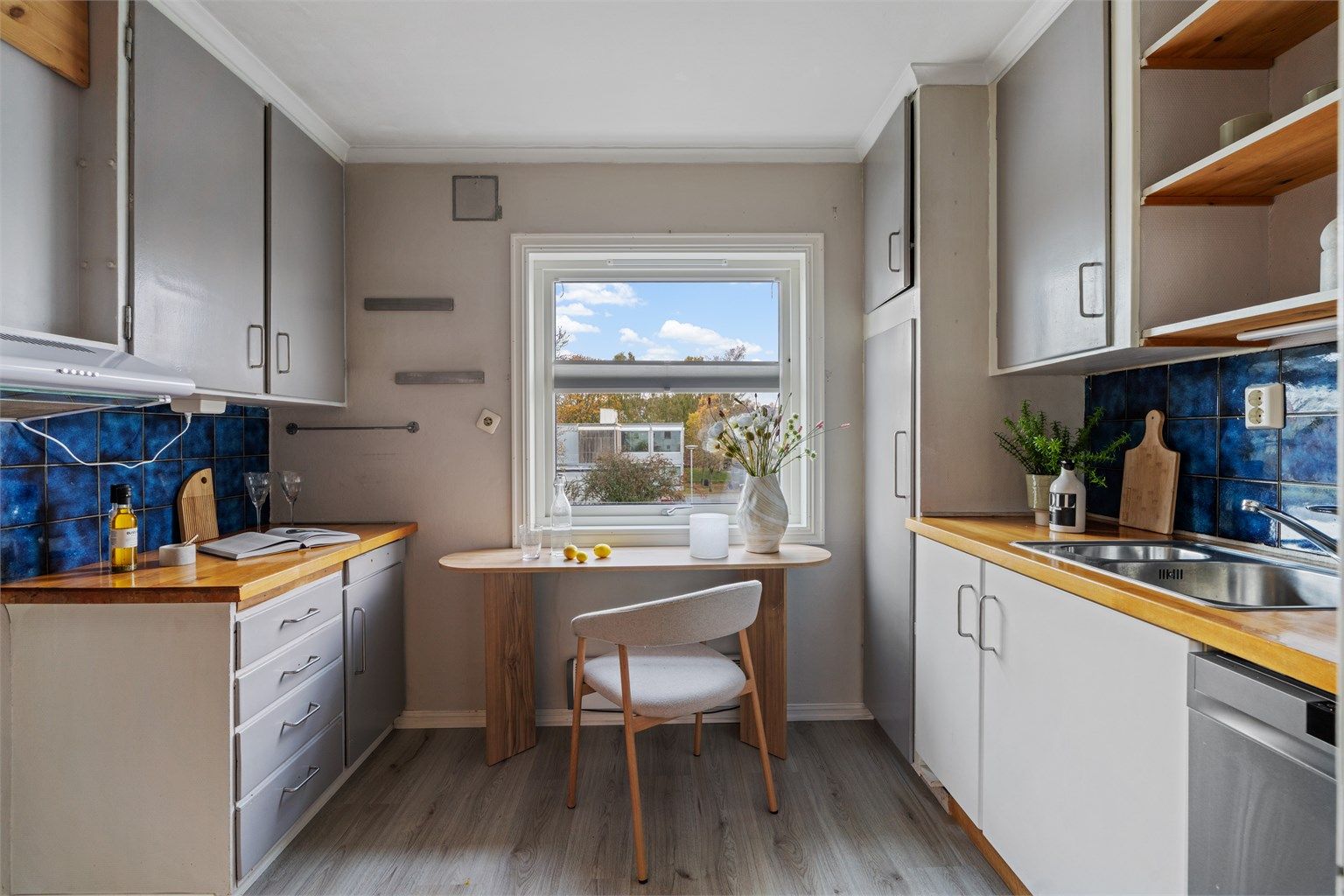 Kjøkken med innredning fra byggeår, benkeplate i tre og vindu mot nabolaget.