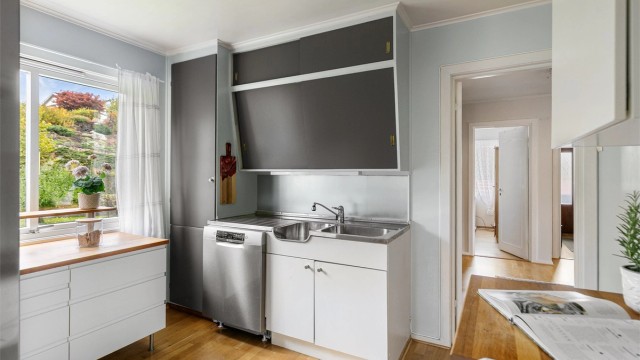 Kjøkkeninnredning fra byggeåret med glatte fronter, oppvaskmaskin og god skapplass.