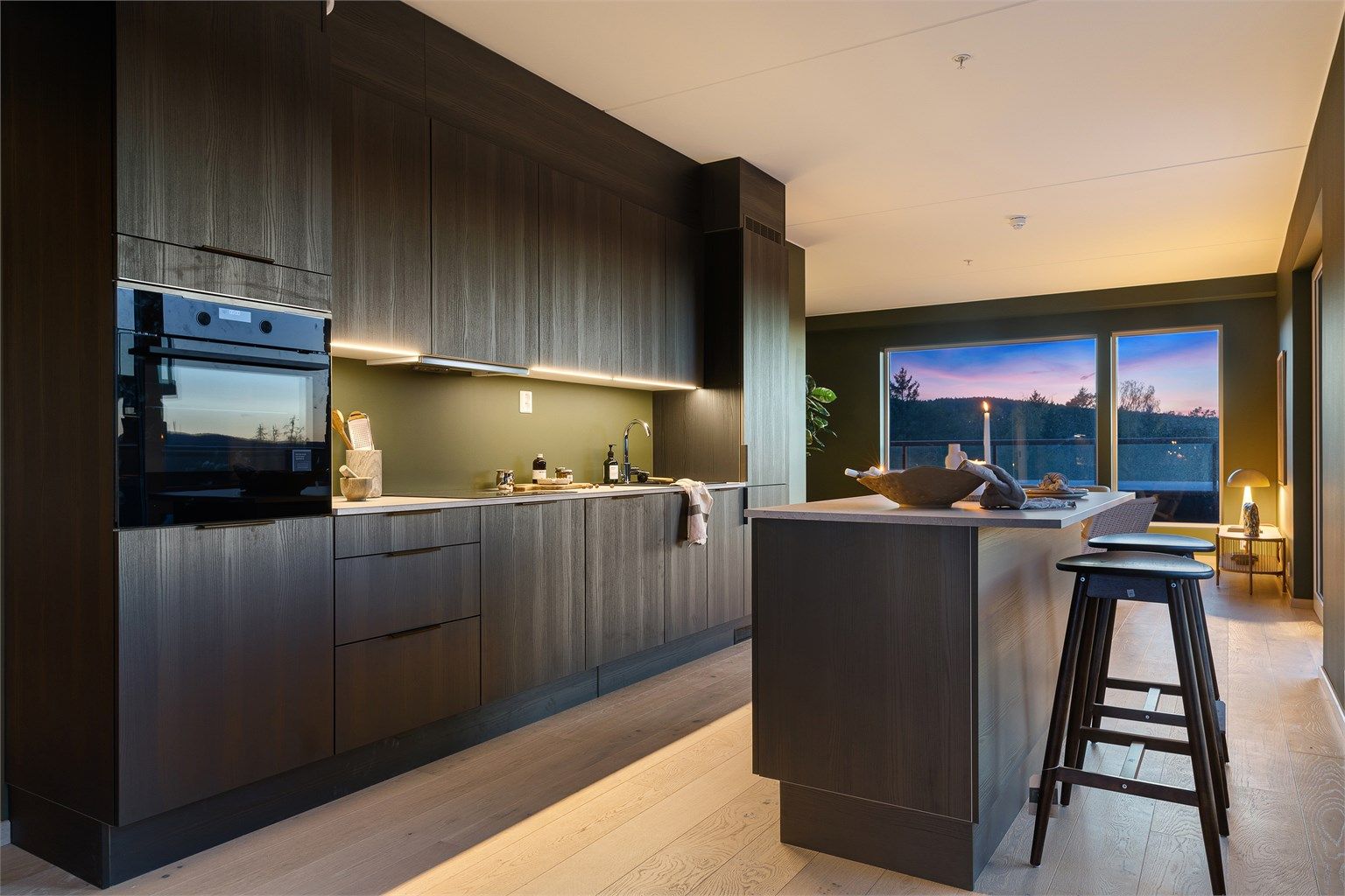 Stilrent og moderne kjøkken med åpen løsning mot spiseplass, som gir en luftig og sosial romfølelse.