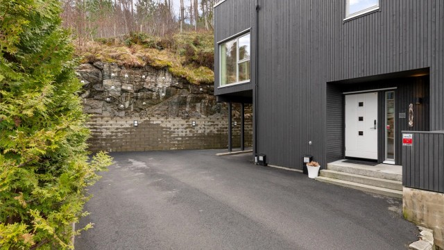 Asfaltert gårdsplass med gode parkeringsmuligheter, inkludert en carport med mulighet for elbillader