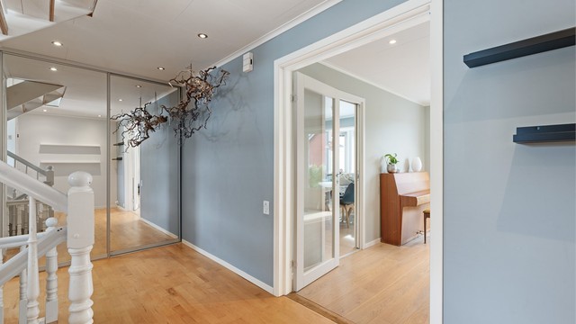 Hallen har garderobeløsning med speilfronter og glassdør inn mot stuen.