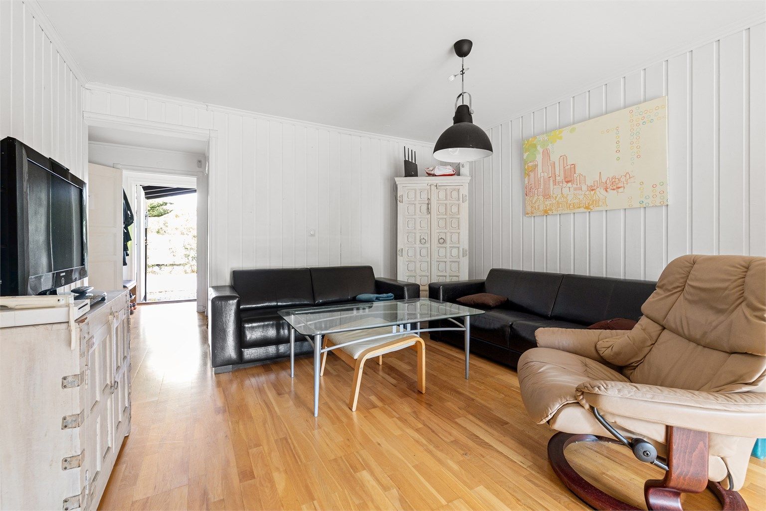 Stuen har god plass til en romslig sofagruppe. Enkelte naboer har åpnet veggen mellom kjøkken og stue for å skape en åpen planløsning.