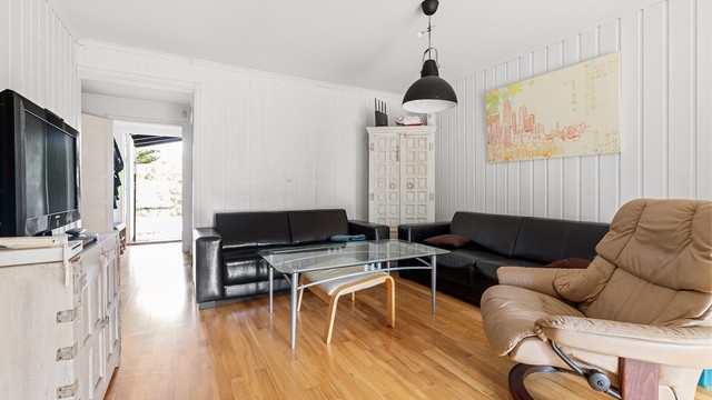 Stuen har god plass til en romslig sofagruppe. Enkelte naboer har åpnet veggen mellom kjøkken og stue for å skape en åpen planløsning.