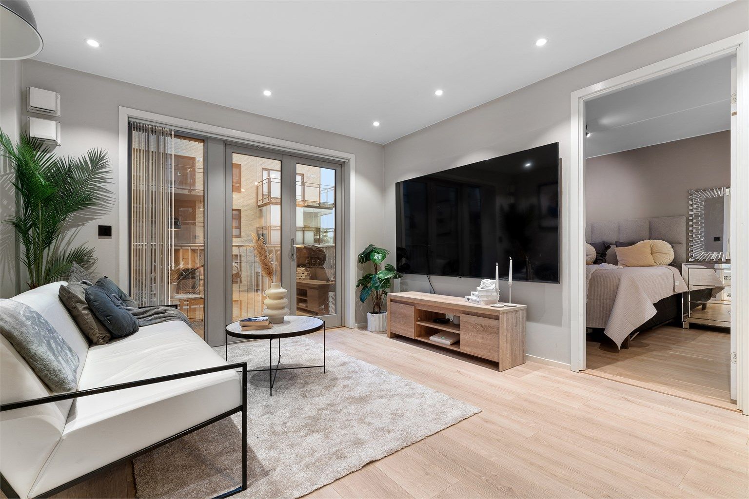 Lys og moderne stue med store vindusflater og downlights i himling. 