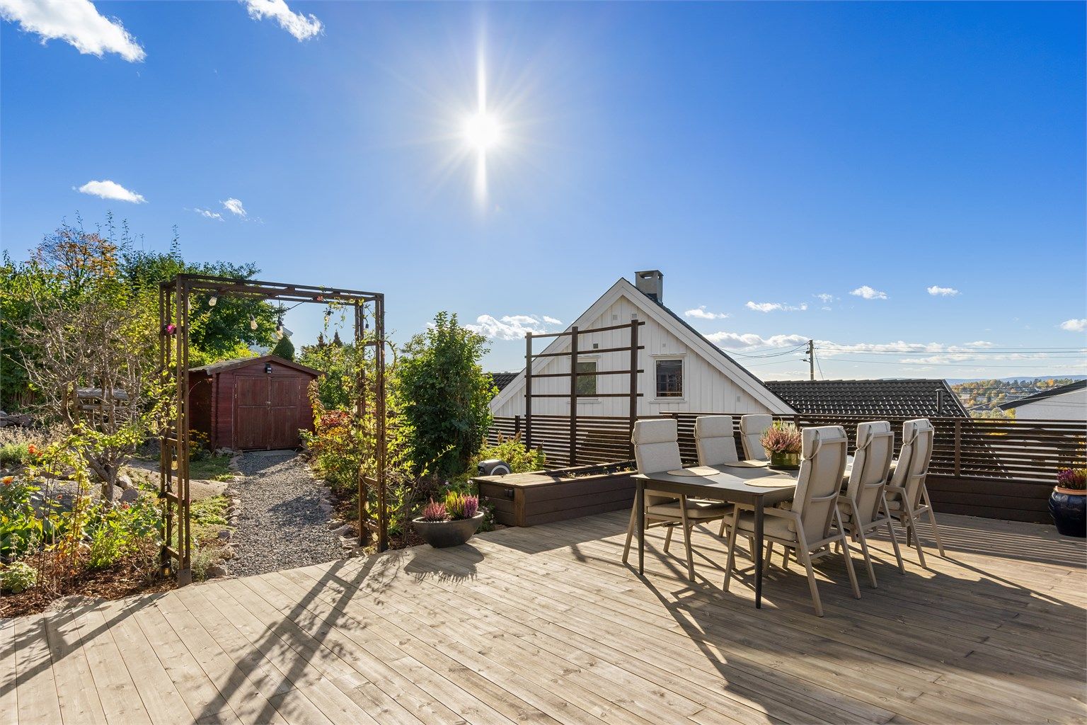 Terrasseplattingen har overgang til hageområde med gruset sti bort til en frittstående utebod.