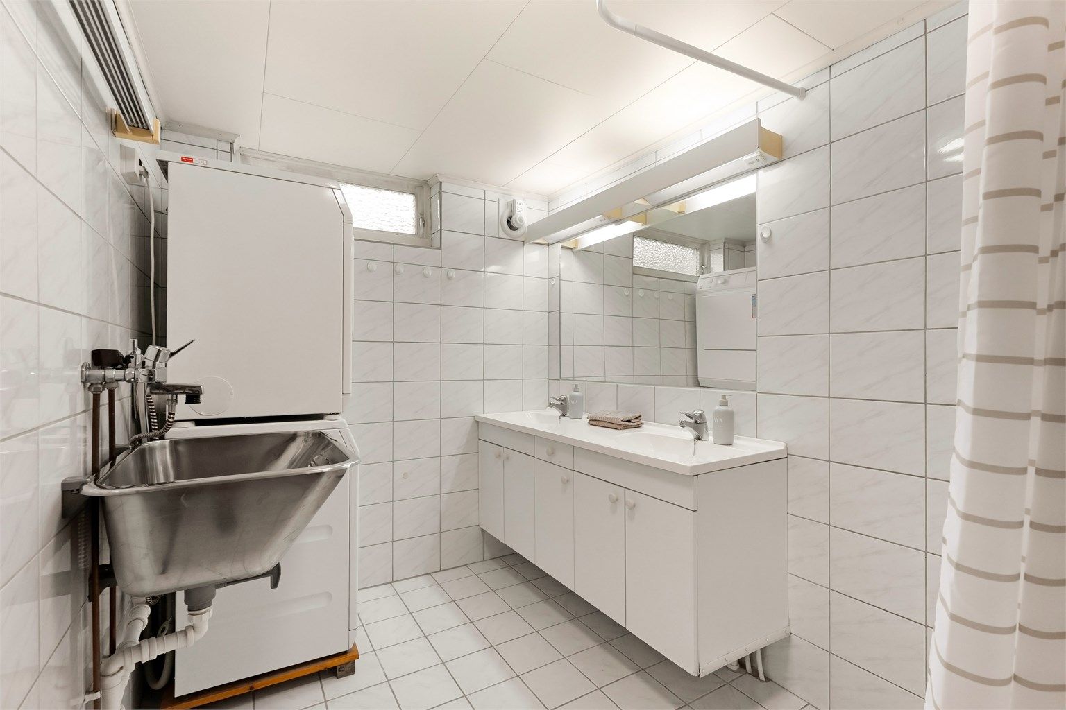 Badet i kjelleren er utstyrt med dobbel servant, utslagsvask og opplegg for vaskemaskin.