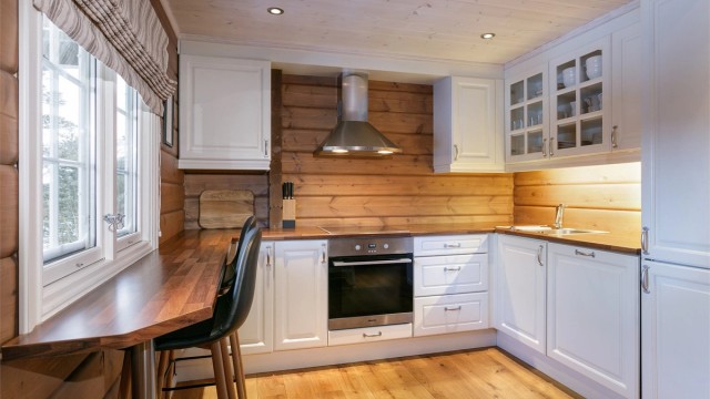 Romslig kjøkken med hvit profilert kjøkkeninnredning med benkeplate av laminat. Det er kjøl/fryseskap, oppvaskmaskin, platetopp og stekeovn.
