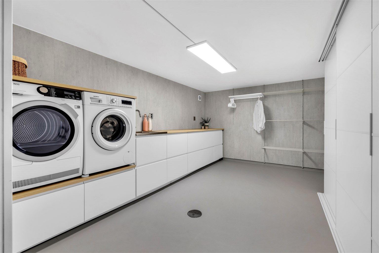 Vaskerommet er stort og nytt med varme i gulvet, gode lagringsmuligheter og tørking av klær i et smart oppheng på vegg. Innredningen på vaskerommet er fra Ikea og har glatte fronter, laminat benkeplate og skyvedørsgarderobe med glatte fronter. 