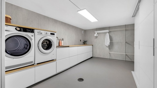 Vaskerommet er stort og nytt med varme i gulvet, gode lagringsmuligheter og tørking av klær i et smart oppheng på vegg. Innredningen på vaskerommet er fra Ikea og har glatte fronter, laminat benkeplate og skyvedørsgarderobe med glatte fronter.
