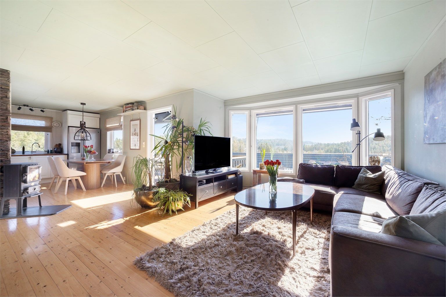 Hovedetasjens åpne løsning mellom stue og kjøkken skaper en lys og sosial sone. Gulvet er belagt med heltregulv.