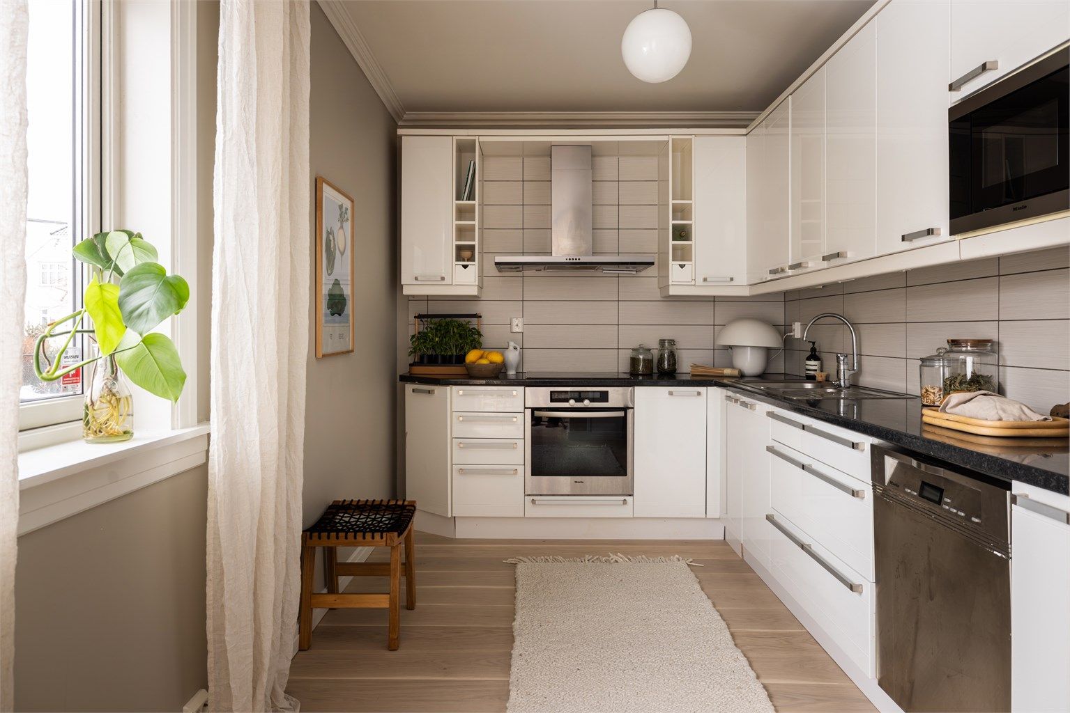 Tidløst kjøkken fra 2005 med integrert platetopp, stekeovn og mikrobølgeovn, samt oppvaskmaskin under benk og frittstående kjøleskap med frysedel