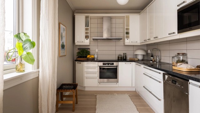 Tidløst kjøkken fra 2005 med integrert platetopp, stekeovn og mikrobølgeovn, samt oppvaskmaskin under benk og frittstående kjøleskap med frysedel