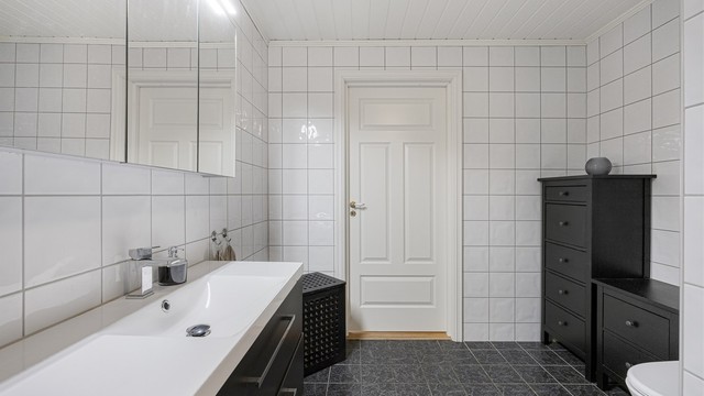 Heldekkende servant over servantskap med glatte, folierte fronter. Varmtvannsberederen på 194 liter fra 2008 er plassert på badet.