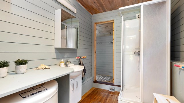 Badet er utstyrt med dusjkabinett, servant og mekanisk avtrekksvifte.