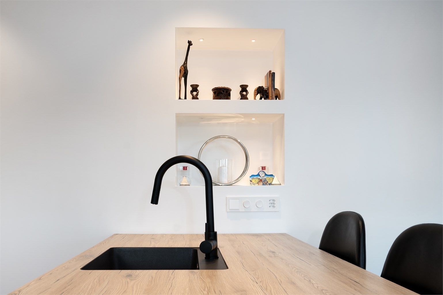 Innfelte, belyste hyller i veggen gir en dekorativ og praktisk oppbevaringsløsning.