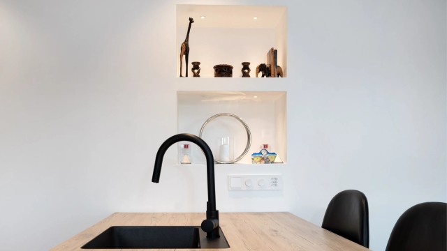 Innfelte, belyste hyller i veggen gir en dekorativ og praktisk oppbevaringsløsning.